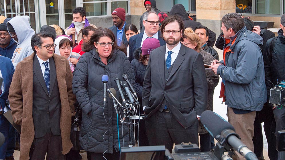 Attorneys for the ACLU, Omar Jadwat(L) and Justin Cox(R) listen as Becca Heller(C) from IRAP, the International Refugee Assistance Project,delivers remarks to the media outside US District Court, Southern District of Maryland, March 15, 2017, in Greenbelt, Maryland, where a judge heard their challenges to US President Trump's Executive Order travel ban