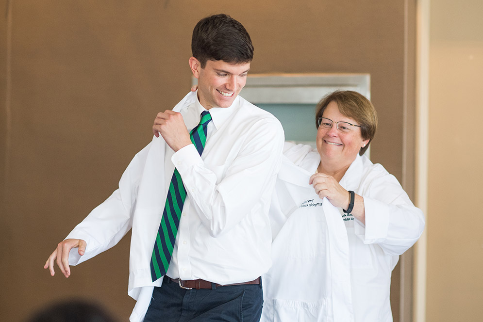 Angela Reffel helping Trevor Dutton put on white coat
