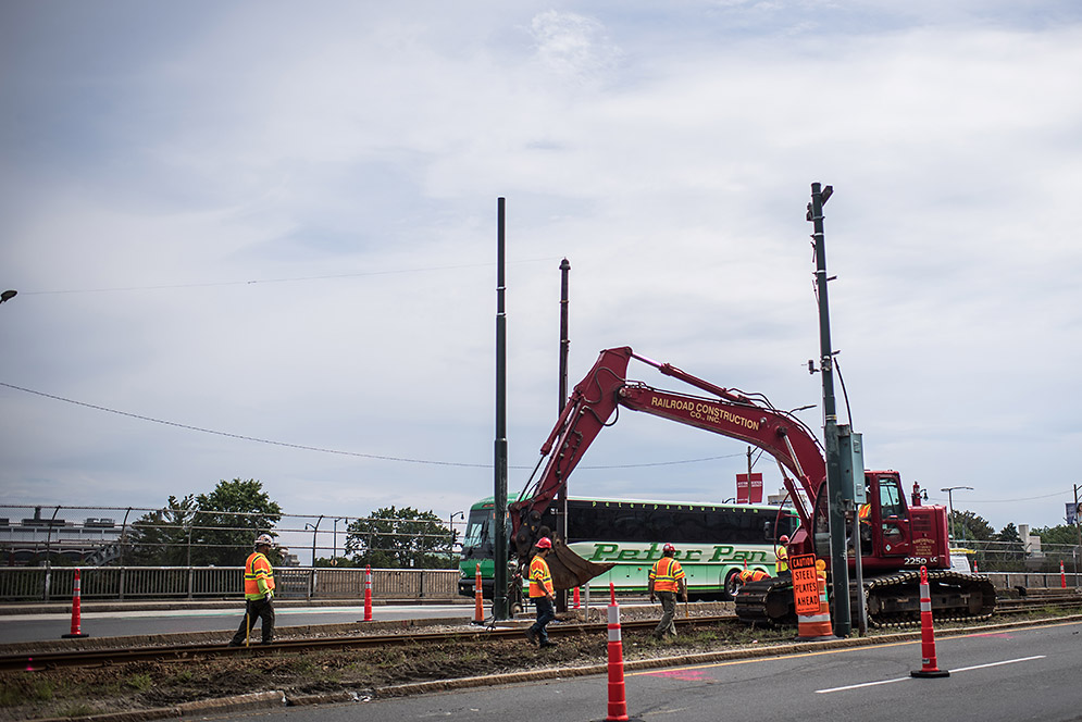 Shuttle bus driving past construction vehicle on Comm Ave