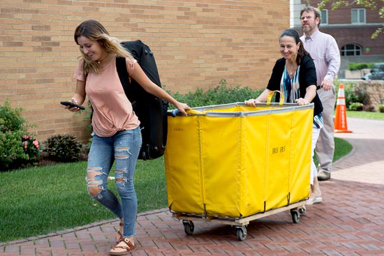 Student guiding a move-in cart with her parents in tow