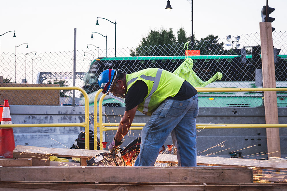 Construction worker circular sawing wood beams