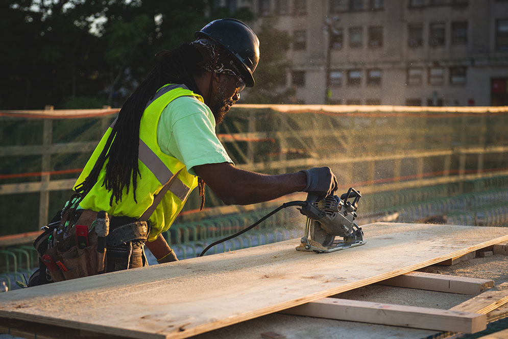 Beautiful shot of a construction worker lit by the golden flecks of sand particles whirring from his machine