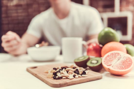 Healthy breakfast containing a fruits, porridge and nuts full of nutrients, guy is eating in the background