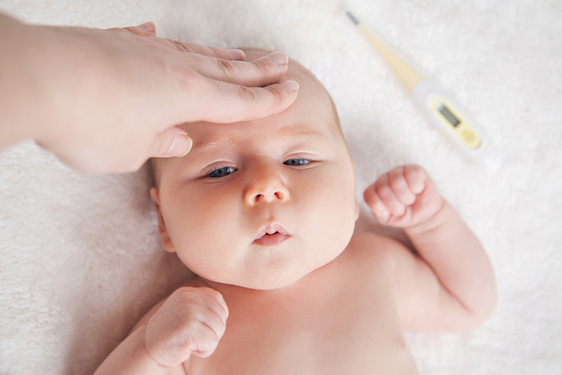 Sick kid with high fever laying in bed while mother checks the temperature