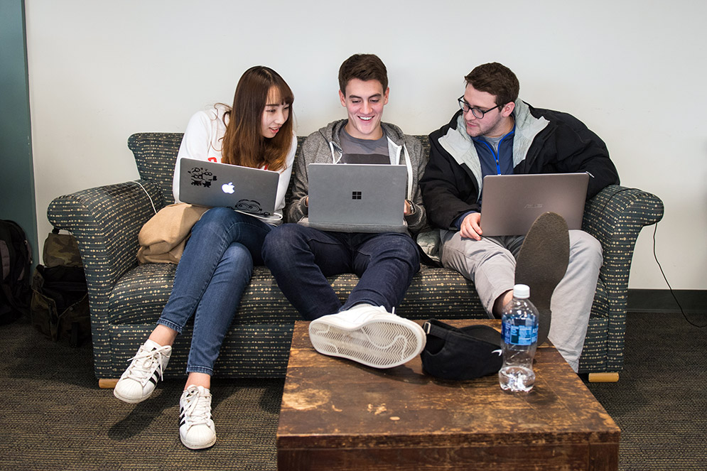 Yunting Cai (Questrom'19), from left, Tomas Fernandez (Questrom'19), and Randy Richardson (Questrom'19) work together in the Dean's Study Lounge at the GSU November 20, 2017 to finalize their business plan for the Questrom Core New Product Challenge. The three, who are part of a ten person team, would be presenting their product, a music festival/rave backpack, the next day. The backpack would include anti-theft pockets, a place for a hydration pack, a poncho and phone charger. "We've been here (working not he plan) for the last five days" said Fernandez.  Photo by Cydney Scott for Boston University Photography