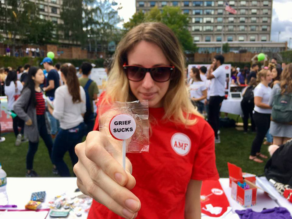 Allison Zuckerberg, President of the BU chapter of Actively Moving Forward holds a lollipop that says Grief Sucks