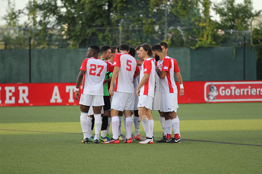 Members of the 2017 BU Terriers men's soccer team huddle during a match