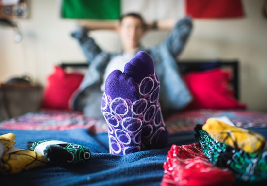 A man relaxes with his feet up, showing off patterned string&&loop socks.