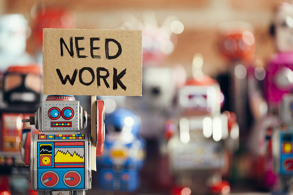 Group of vintage toy robots holding a sign that says Need Work symbolizing robots taking jobs from humans