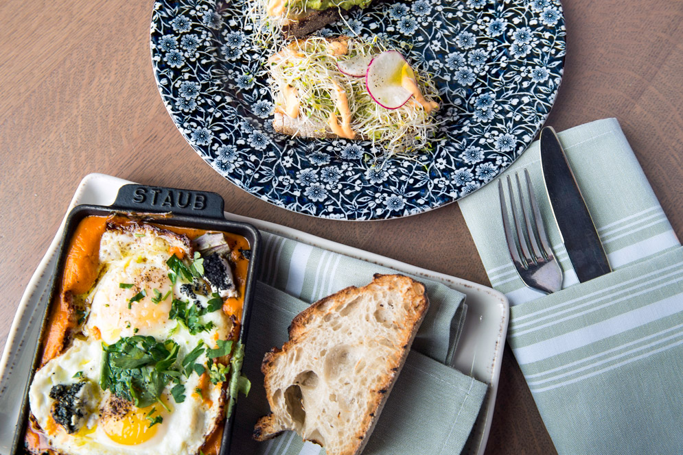 Shakshuka—baked eggs in tomato sauce with charred greens, goat cheese, and French bread.