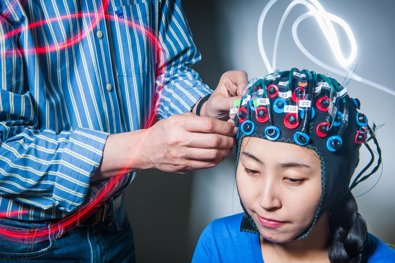 Neurophotonics researcher David Boas connects research fellow Xinge Li to a functional near-infrared spectroscopy (fNIRS) machine.