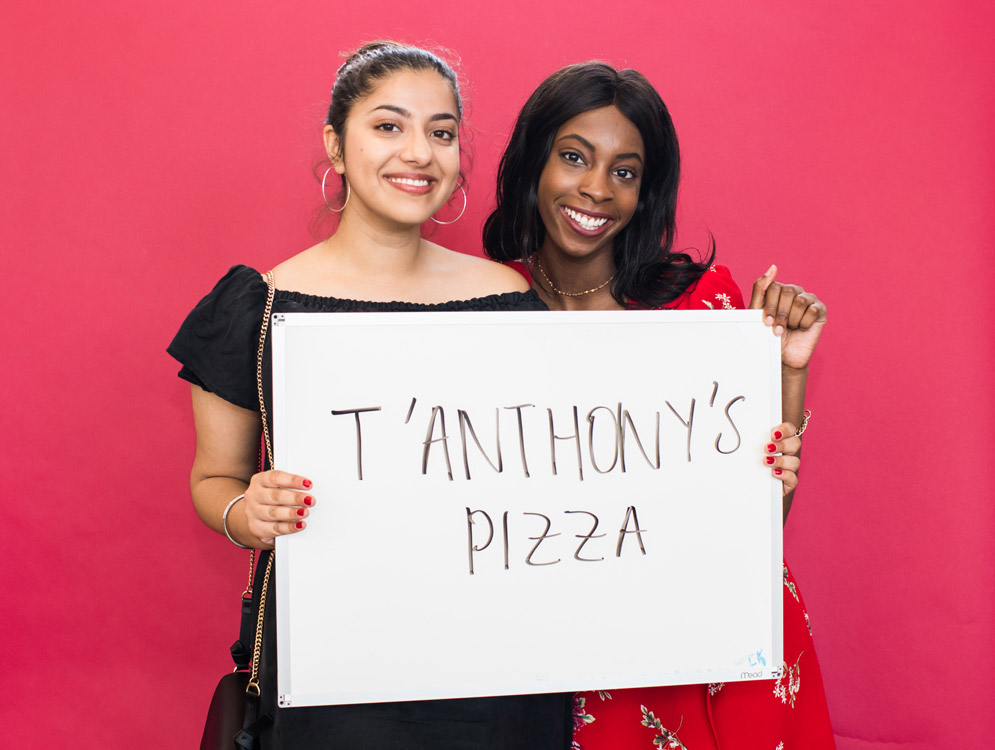 BU graduating seniors hold a sign saying they'll miss pizza from T Anthony's restaurant after they graduate.