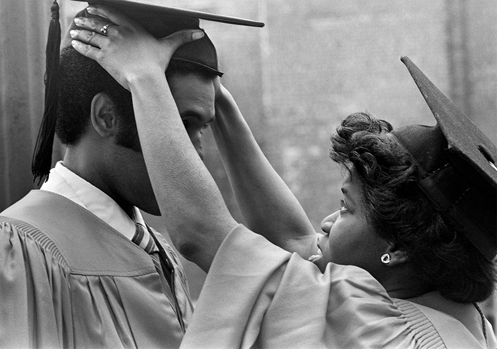 A graduate helps a fellow student adjust his mortarboard at the BU Commencement on Nickerson Field on May 18, 1980.
