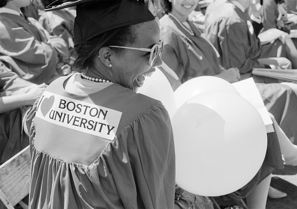 A graduate smiles with a I Love BU bumper sticker and balloons during Commencement on May 13, 1984.