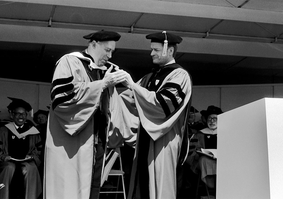 John Silber lights Honorary Degree Recipient Red Auerbach's Cigar at the 1984 Boston University Commencement.