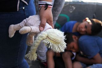 A Mexican woman holds a doll next to children at the Paso Del Norte Port of Entry, in the US-Mexico border in Chihuahua state, Mexico on June 20, 2018