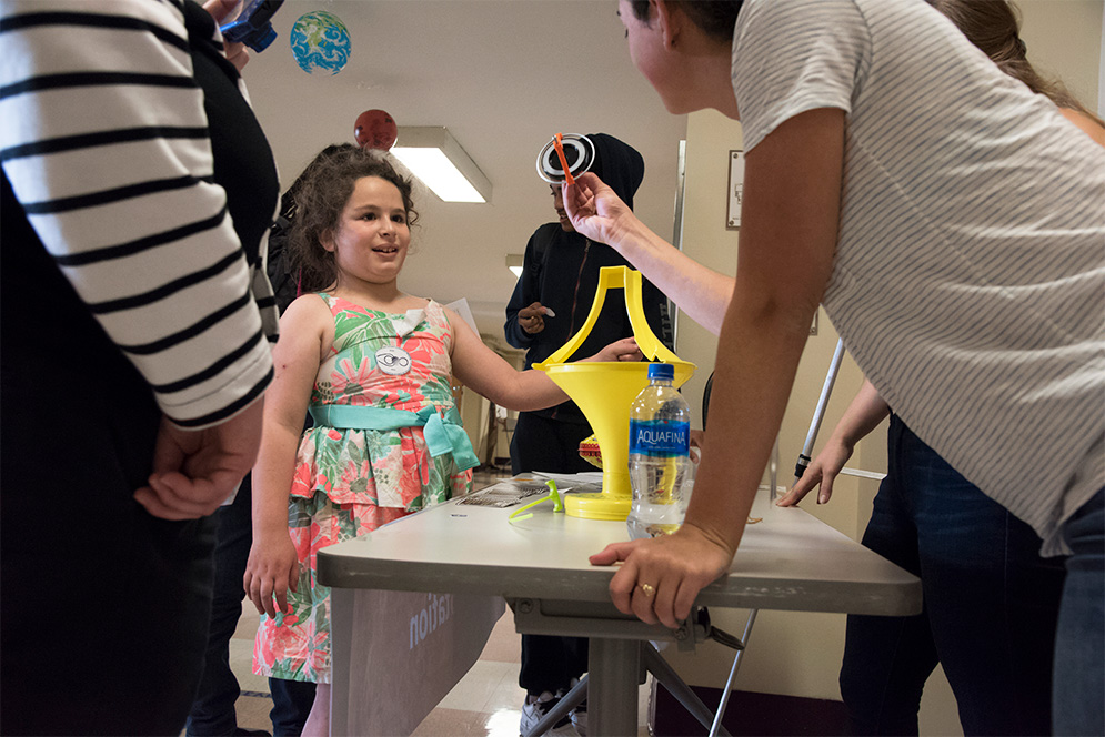 A BU student shows a gyroscope to a child at the Space Science for Kids event.