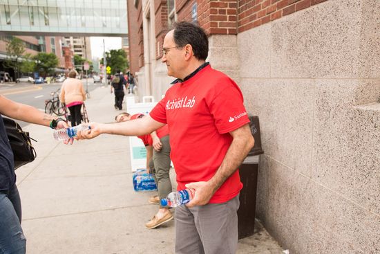 Water Squad volunteer hands water out to a passerby.