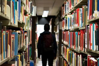 A student with a backpack walks through a library