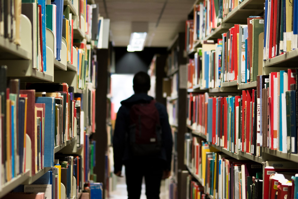 A student with a backpack walks through a library