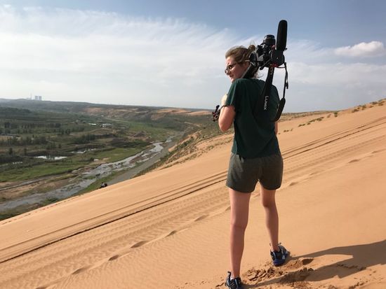 Brianna Burns (CGS’17, COM’19) carrying video gear through the desert