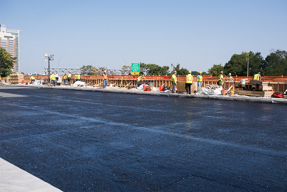 Construction workers build a parapet wall on the westbound side of the Commonwealth Ave. Bridge.