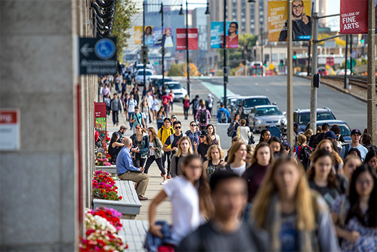 A crowd of students walk along Commonwealth Ave. on the Boston University Charles River Campus.