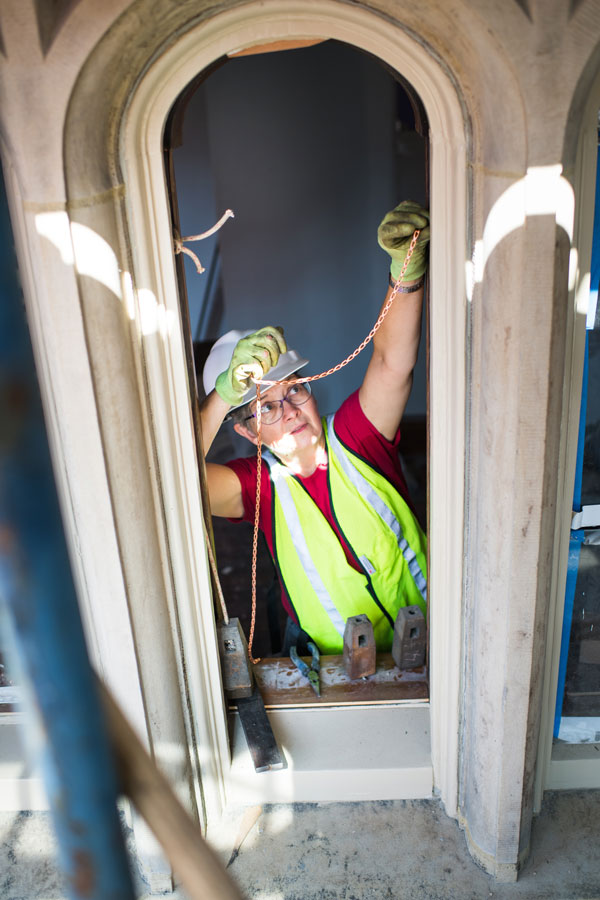 Alison Hardy (Questrom ) installs windows at BU Castle on Monday, July 2, 2918. She is the owner of Window Woman of New England, which has been hired as a subcontractor to restore the windows of the Castle. Photo by Jackie Ricciardi