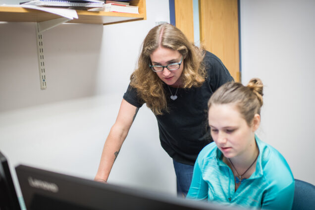 Emily Ryan and a graduate students look intently at a computer screen