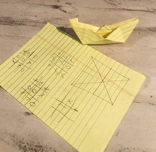 Tic-tac-toe and paper boats made out of legal pad paper
