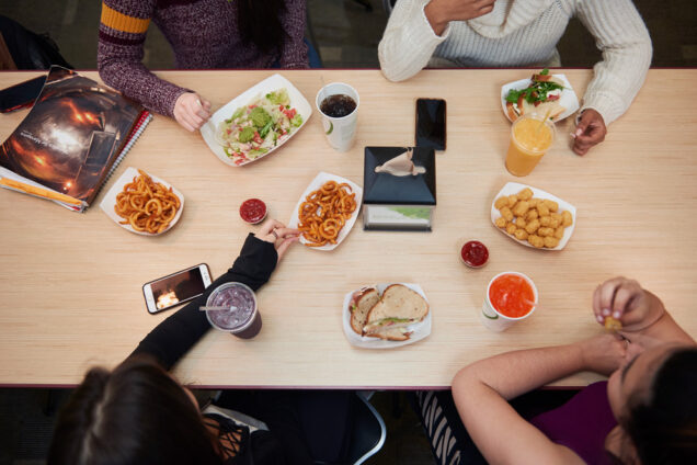 Students gather at a table with food