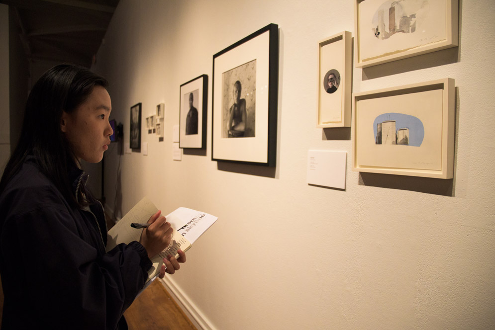 A student reacts to watercolor painting at the opening reception for "Under a Dismal Boston Skyline"