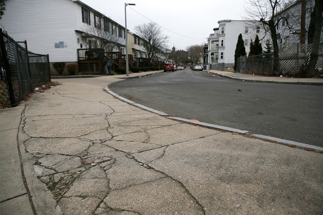 The cracked sidewalk outside of the entrance to the playground behind the Trotter School in the Dorchester neighborhood of Boston