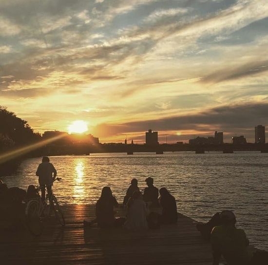 Students gather by the Charles River at sunset