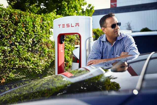 Alum Parag Vaish rests his arms on a Tesla