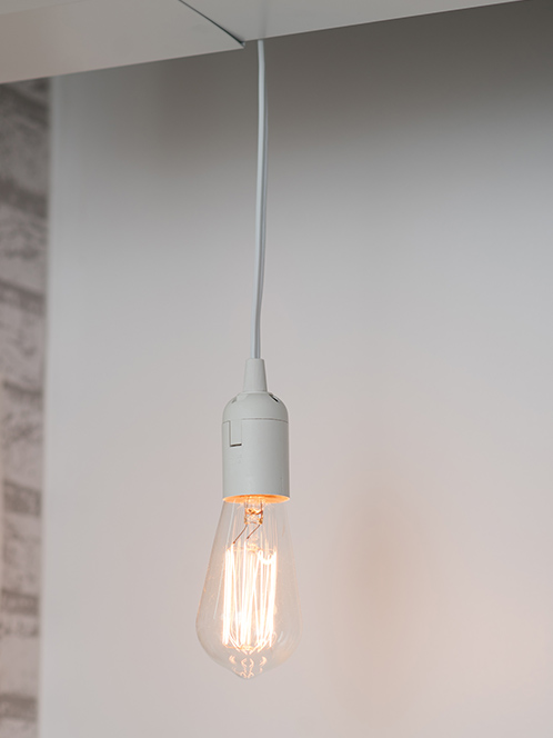 An Edison bulb lit and hanging from a pendant attached to the celing.