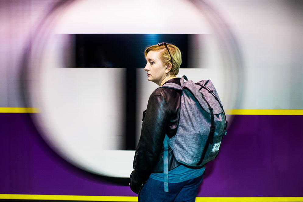 student standing in front of the T logo of a commuter rail station