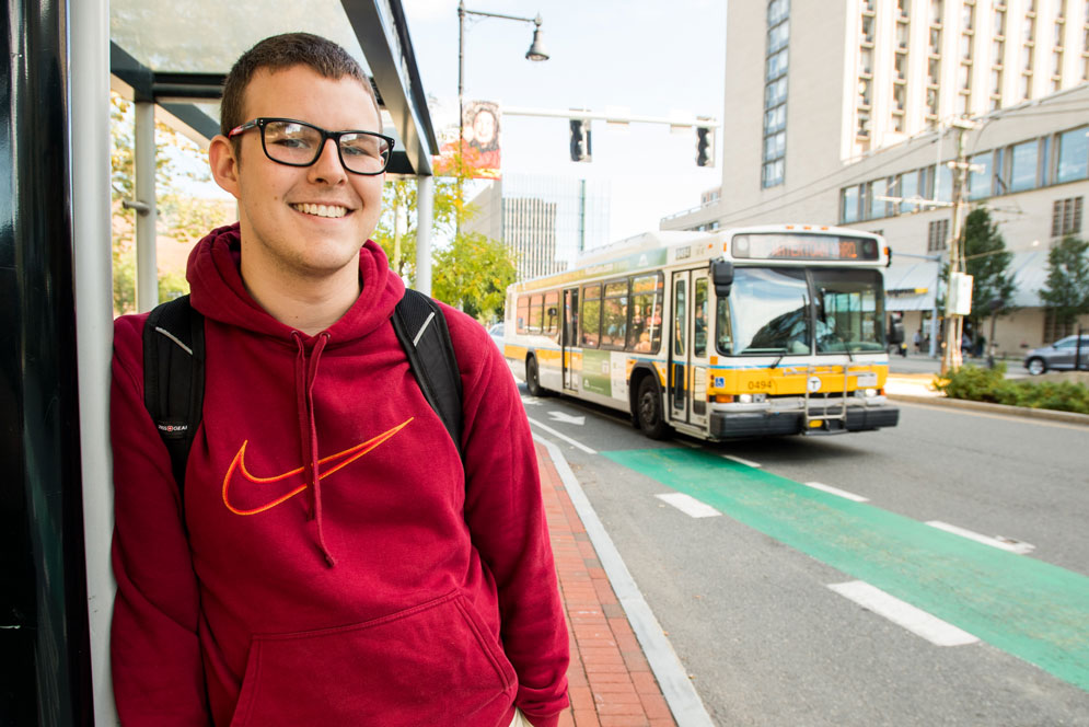 Student standing in front of an mbta bus