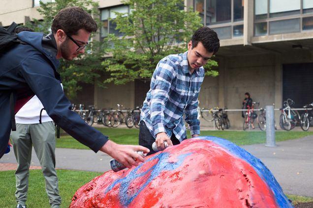 Members of Chi Pai paint the symbol of the pledged fraternity onto the frat rock