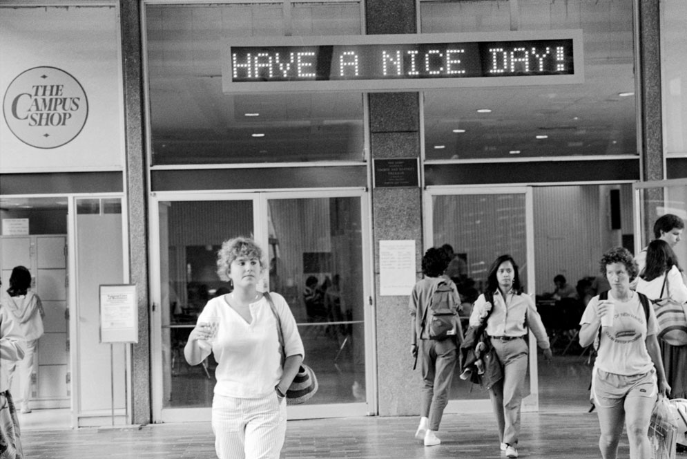 Students walk past the electronic board in the GSU, which reads "Have a Nice Day!"