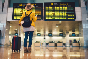 female traveler standing underneath the list of departures and arrivals in an airport