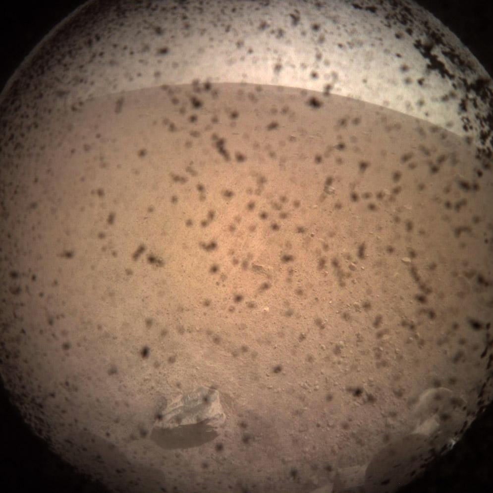 The first photo taken by the NASA InSight Lander upon landing on the Mars surface shows indiscernible surface texture.