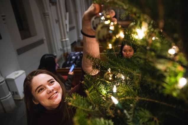 A girl hangs an an ornament during the Marsh Chapel Christmas Tree Trimming 
