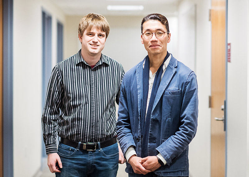 Computer scientists Jacob Harer and Peter Chin pose for a portrait in a classroom building hallway