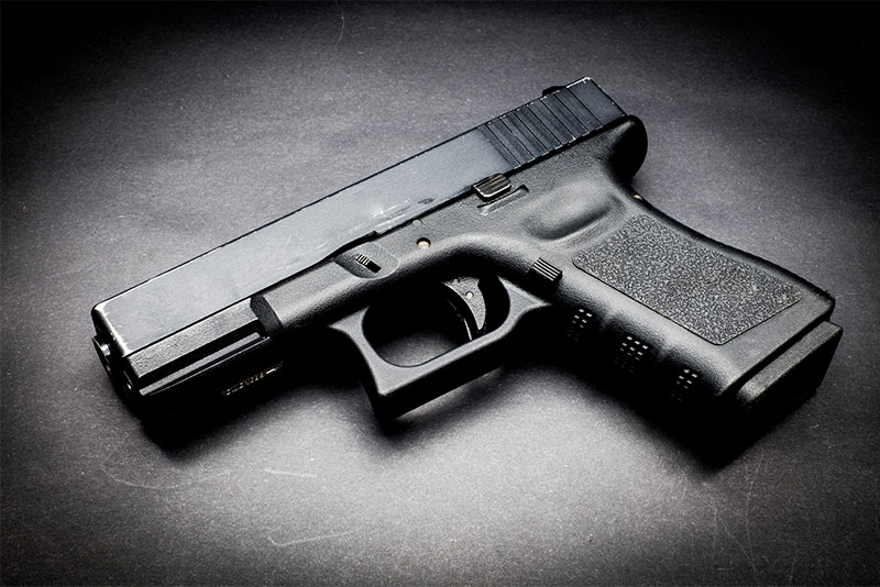 Black handgun lying on a black background