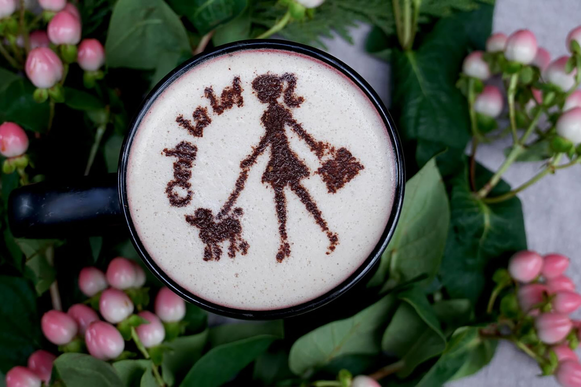 Photo: A cup of coffee with a design in the foam that looks like a woman walking a dog with the text "Ooh La La" above their head