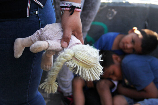 An immigrant holds a child's doll at the border