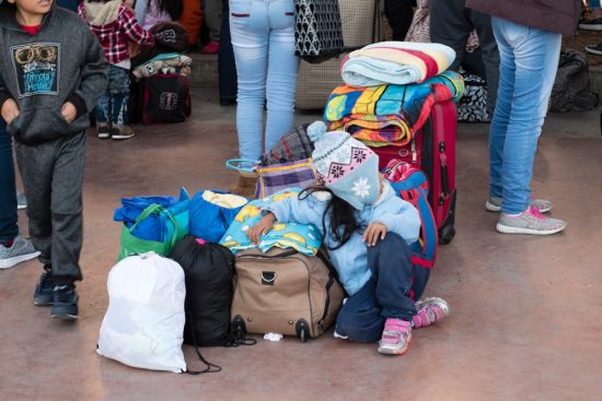 A child sits on the floor surrounded by luggage