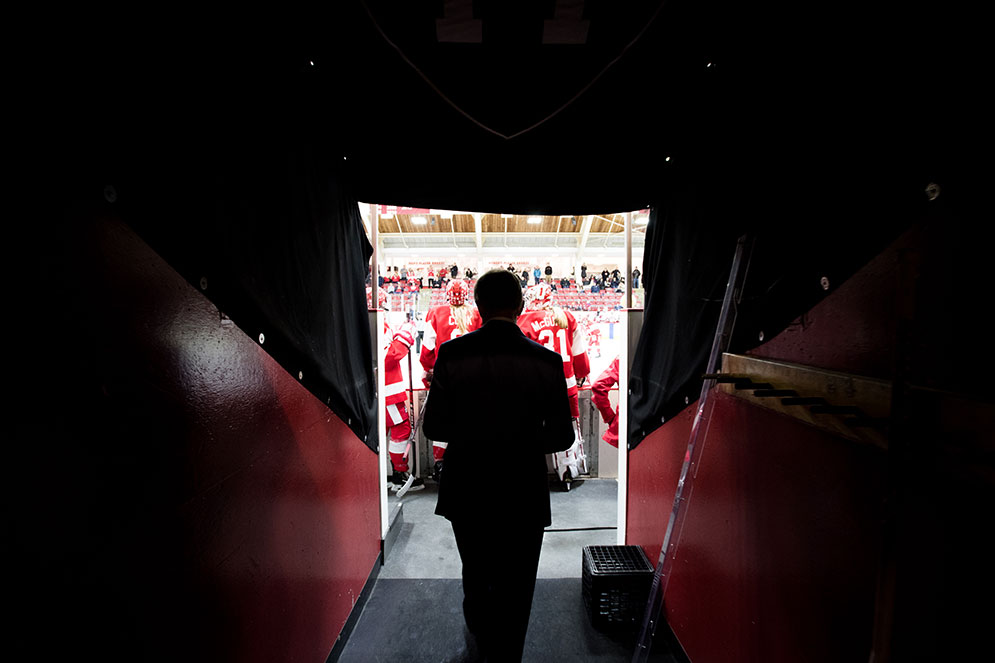 Silhouetted against the area light, BU women's ice hockey head coach Brian Durocher walks out to the Boston University bench at the start of sudden death overtime.