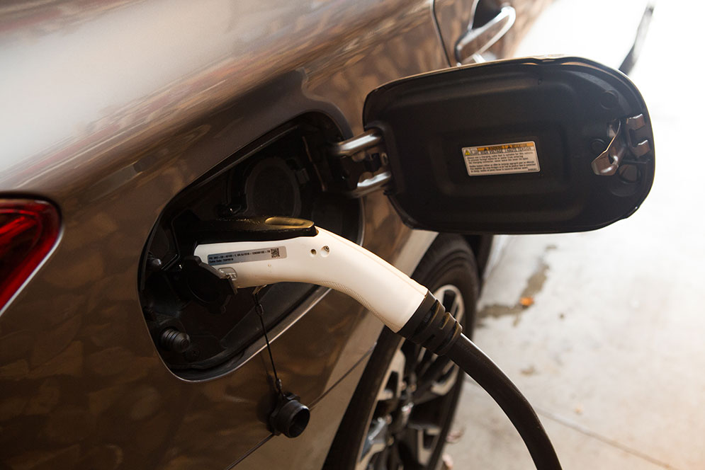Detail view of the solar charging plug inserted into the plug of the Mitsubishi Outlander PHEV hybrid vehicle.